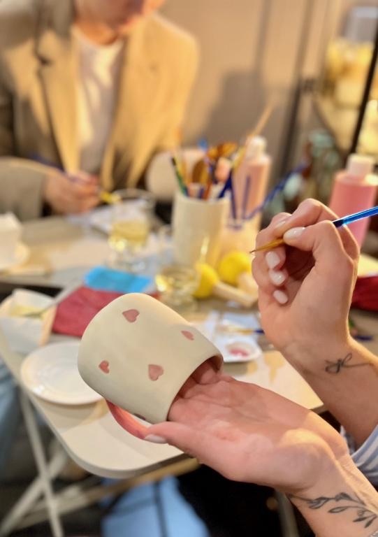 Une participante décore une tasse en céramique avec un pinceau lors d’une séance Place au décor